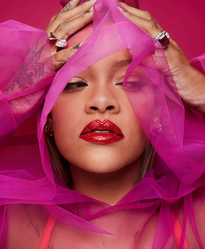 Rihanna in Gloss Bomb Stix Gloss Stick in shade The MVP holding pink mesh around her head.