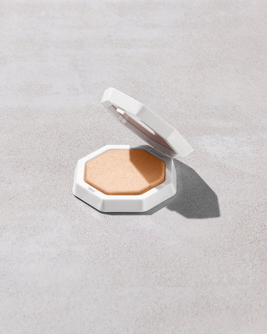 Open product shot of Demi'glow Light-Diffusing Highlighter in shade Prosecco on a concrete backdrop.